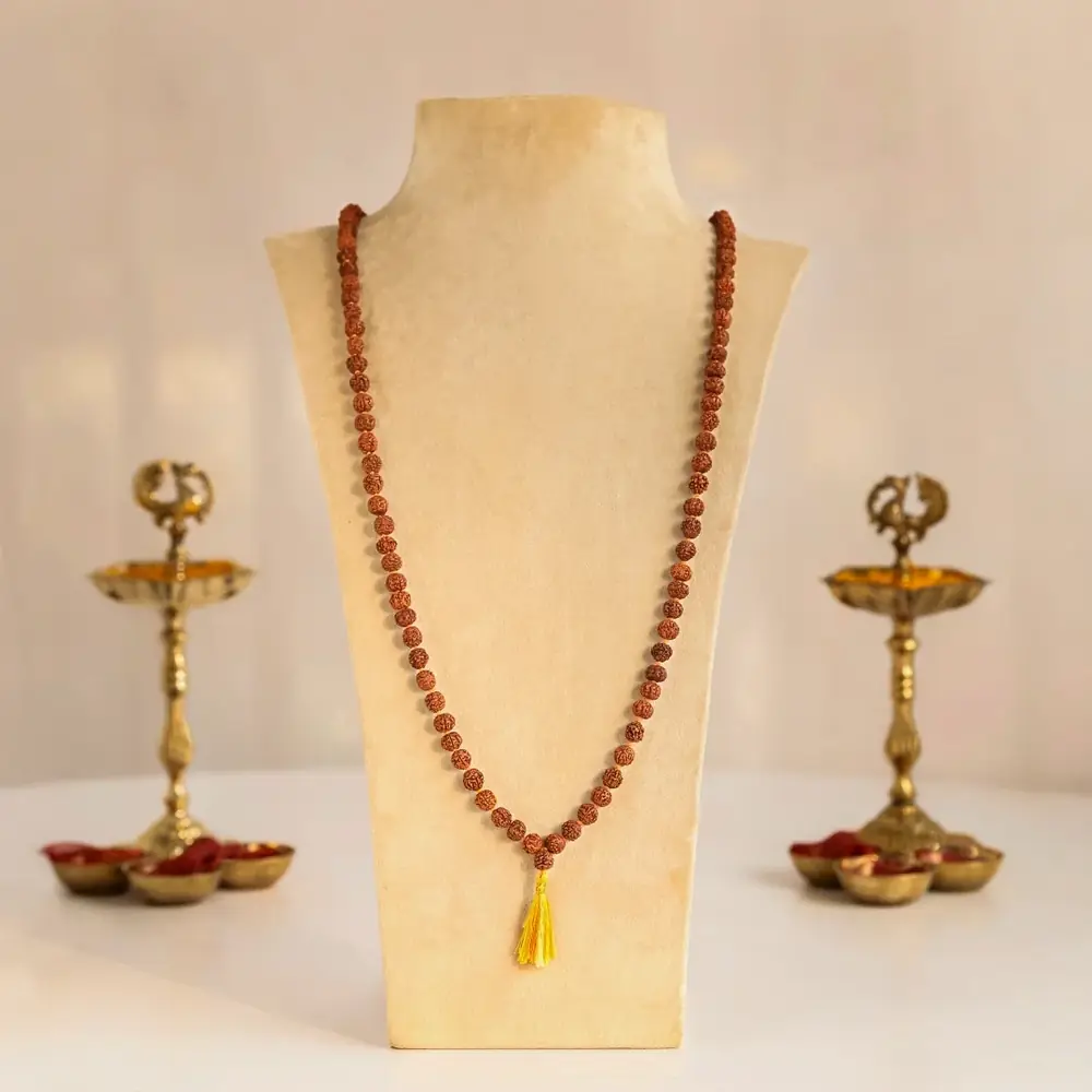 Rudraksha mala on a display stand between two brass lamps