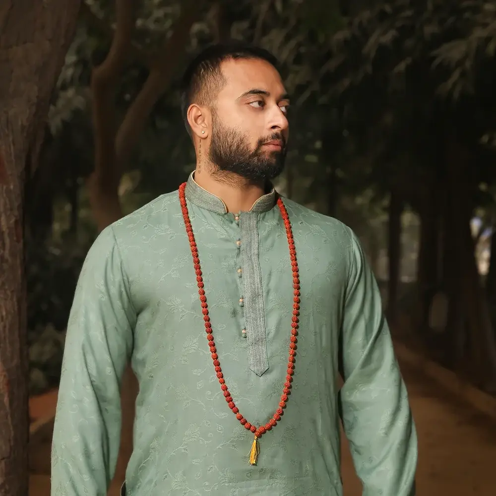 A man wearing the rudraksha mala with a green kurta