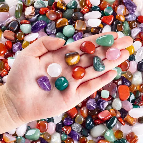 A hand holding a pile of colourful tumbled stones