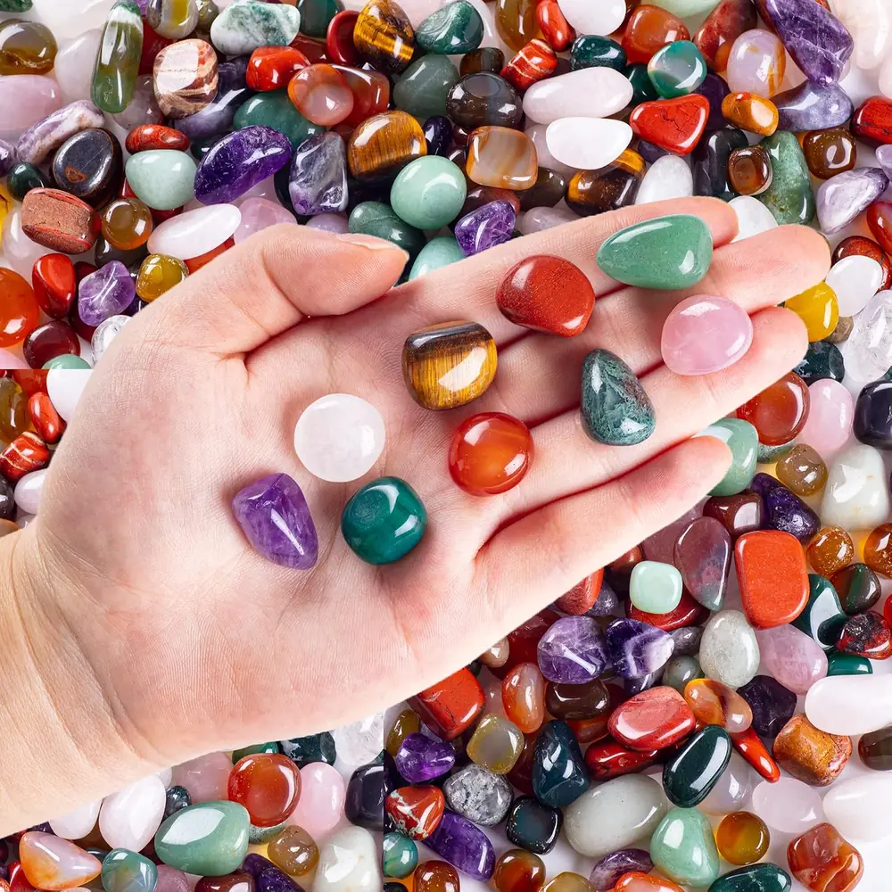 A hand holding a pile of colourful tumbled stones