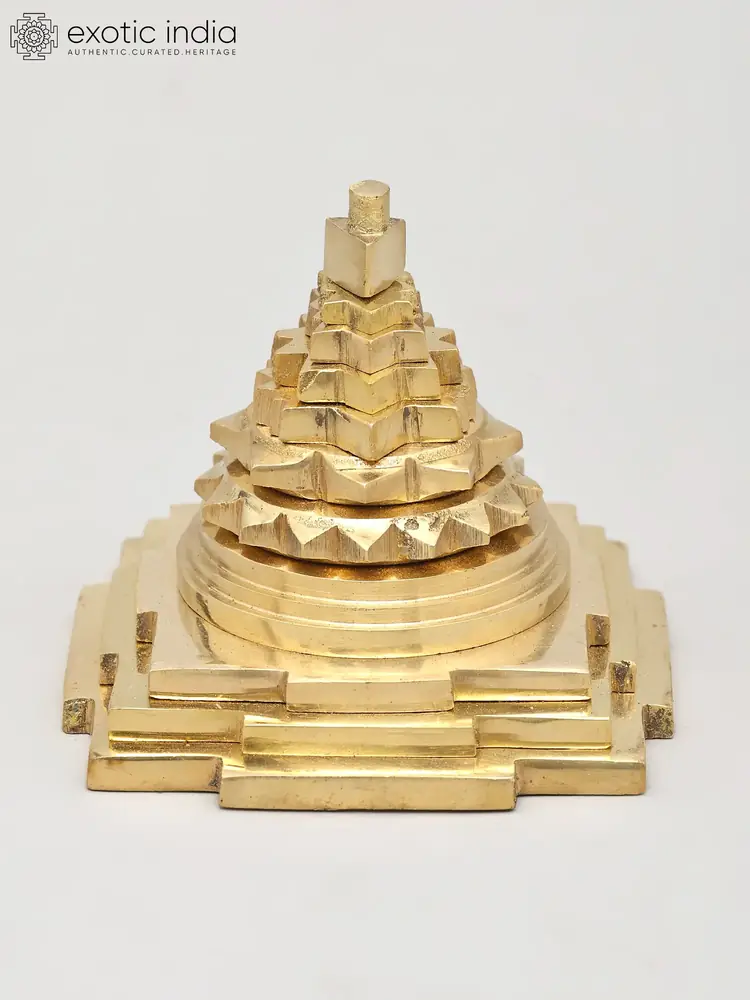 Polished brass Shri Yantra seen from the side on a pale ground