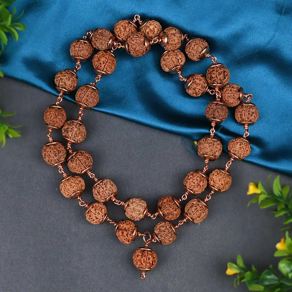 Long loop of copper wired rudraksha beads on a grey and blue ground