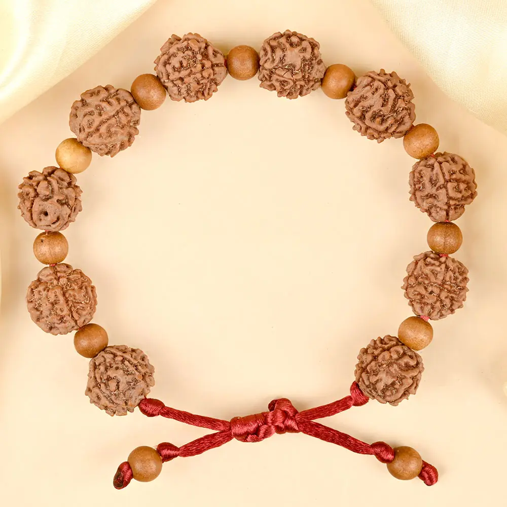 Bracelet of rudraksha and sandalwood beads with a red cord laid flat