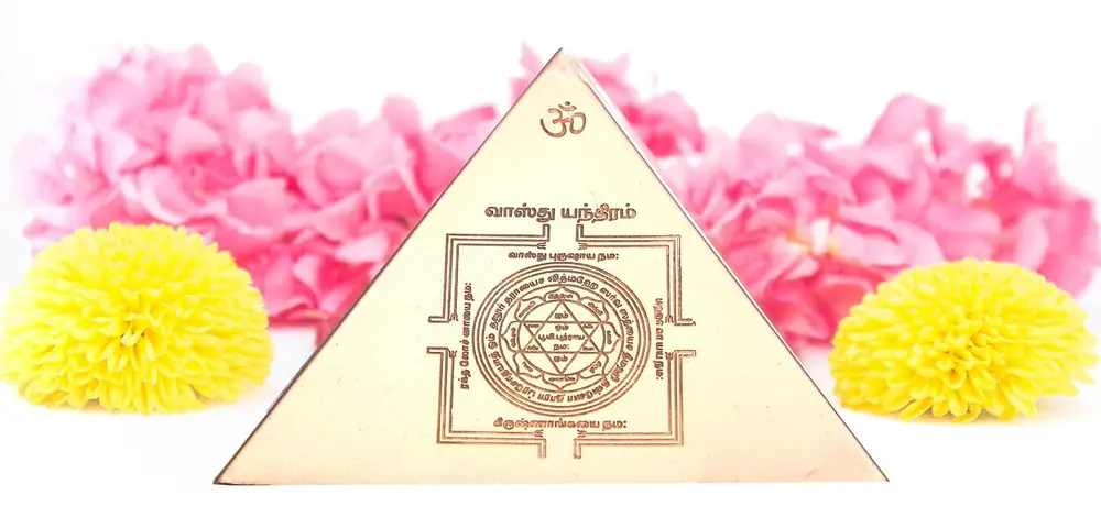 Pyramid face with a carved yantra, shown on pink flowers