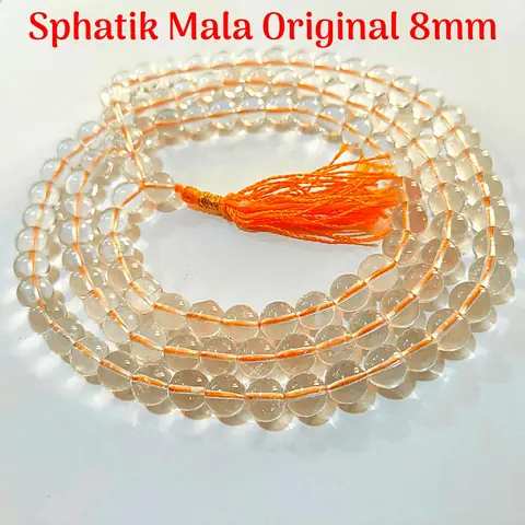 Round clear beads and an orange tassel on a red ground