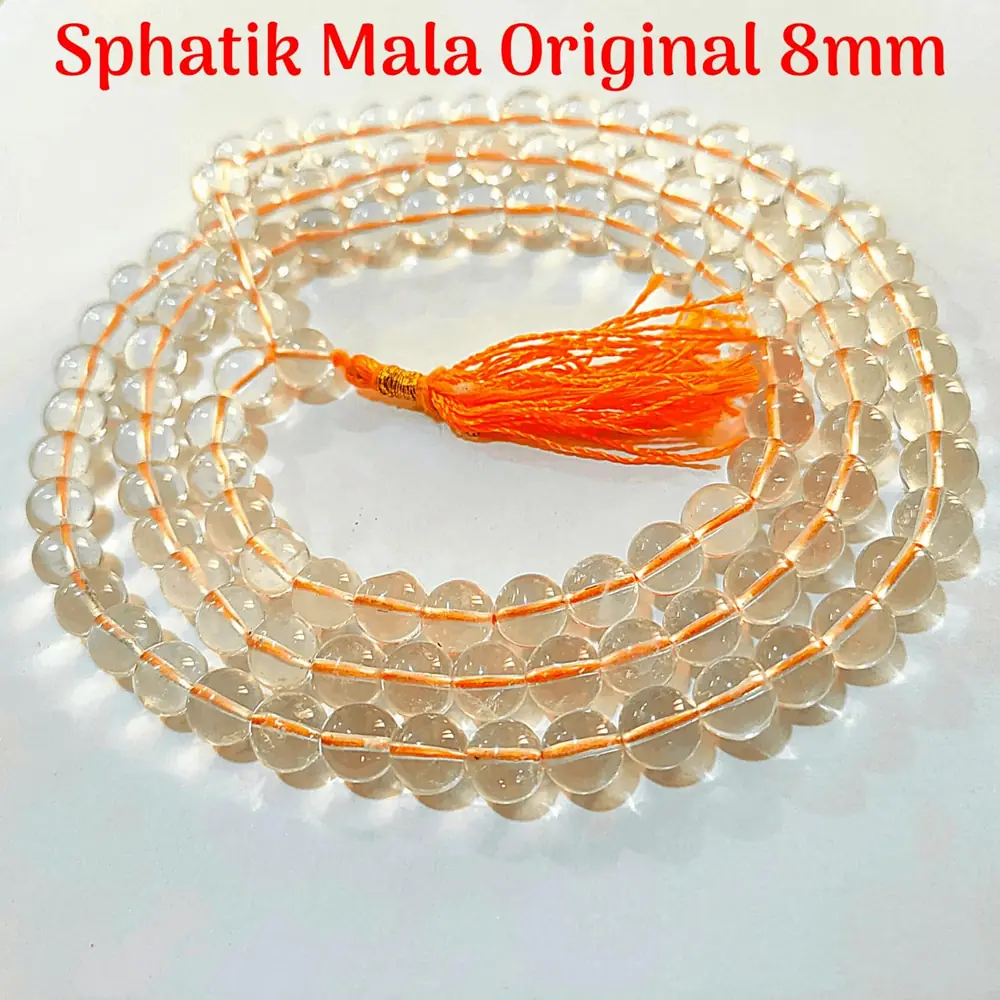 Round clear beads and an orange tassel on a red ground