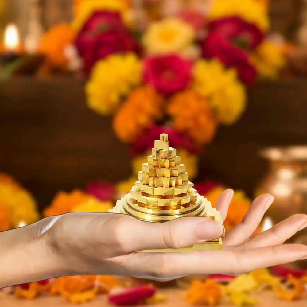 The yantra held in a hand beside marigold flowers