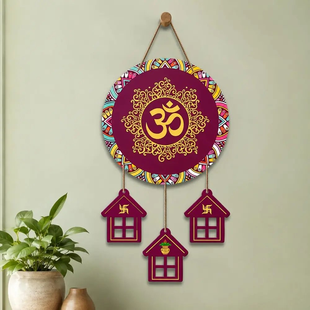 Maroon and gold Om wall hanging on a light wall beside a plant