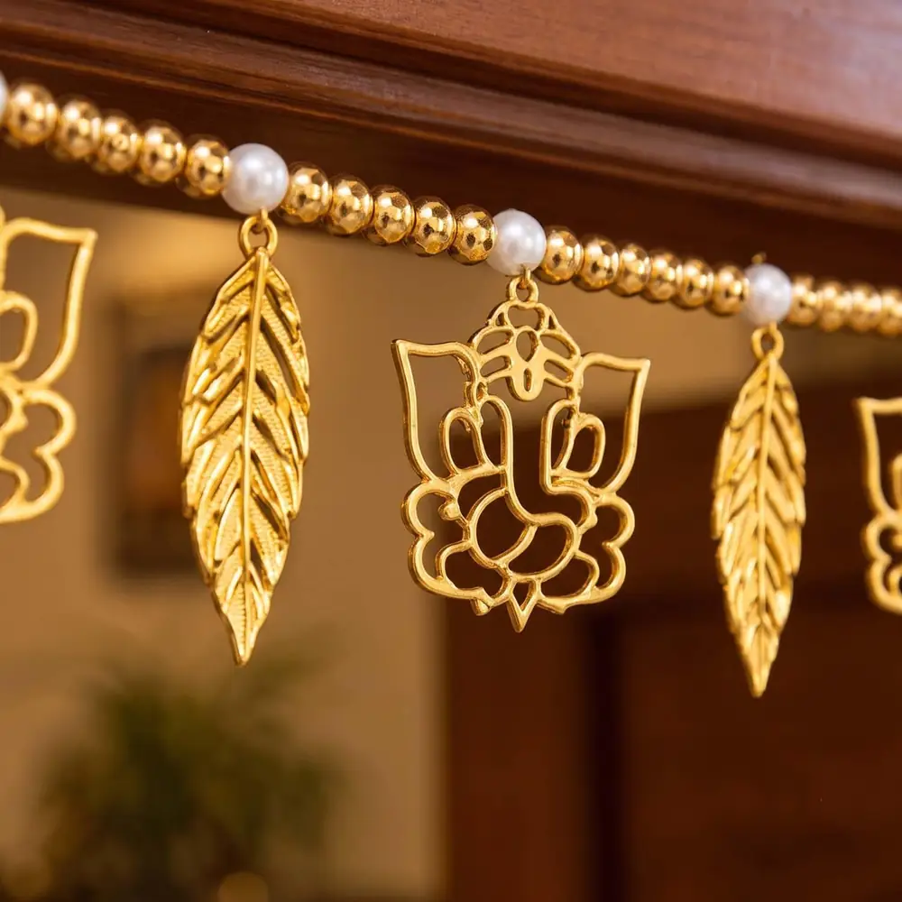 Close view of a gold Ganesha figure and leaf pieces on beaded string