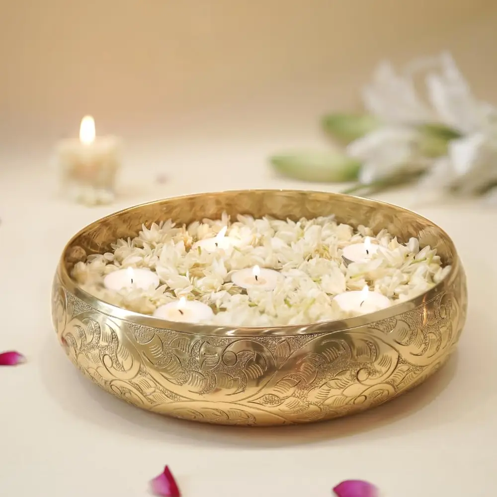 Golden chitai urli bowl filled with white flowers on a table