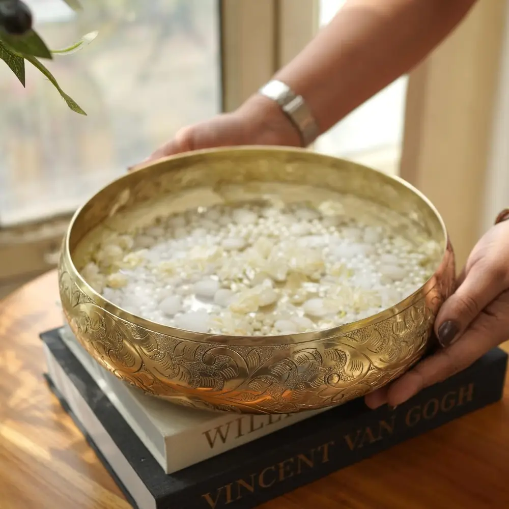 A hand lifting the urli bowl to show its size