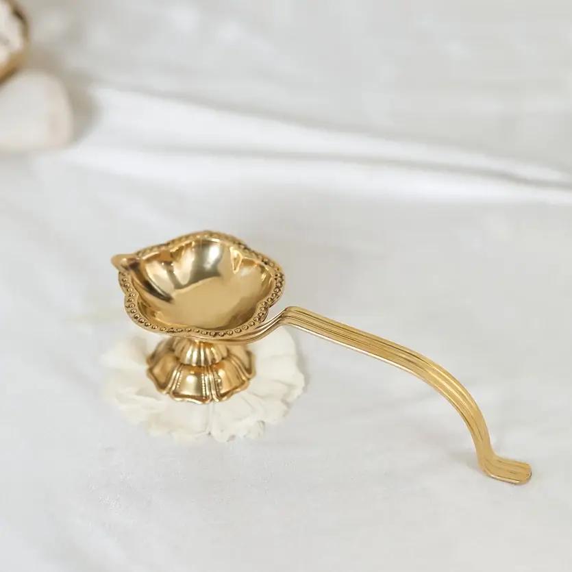 Brass aarti diya on a white cloth, seen from the front
