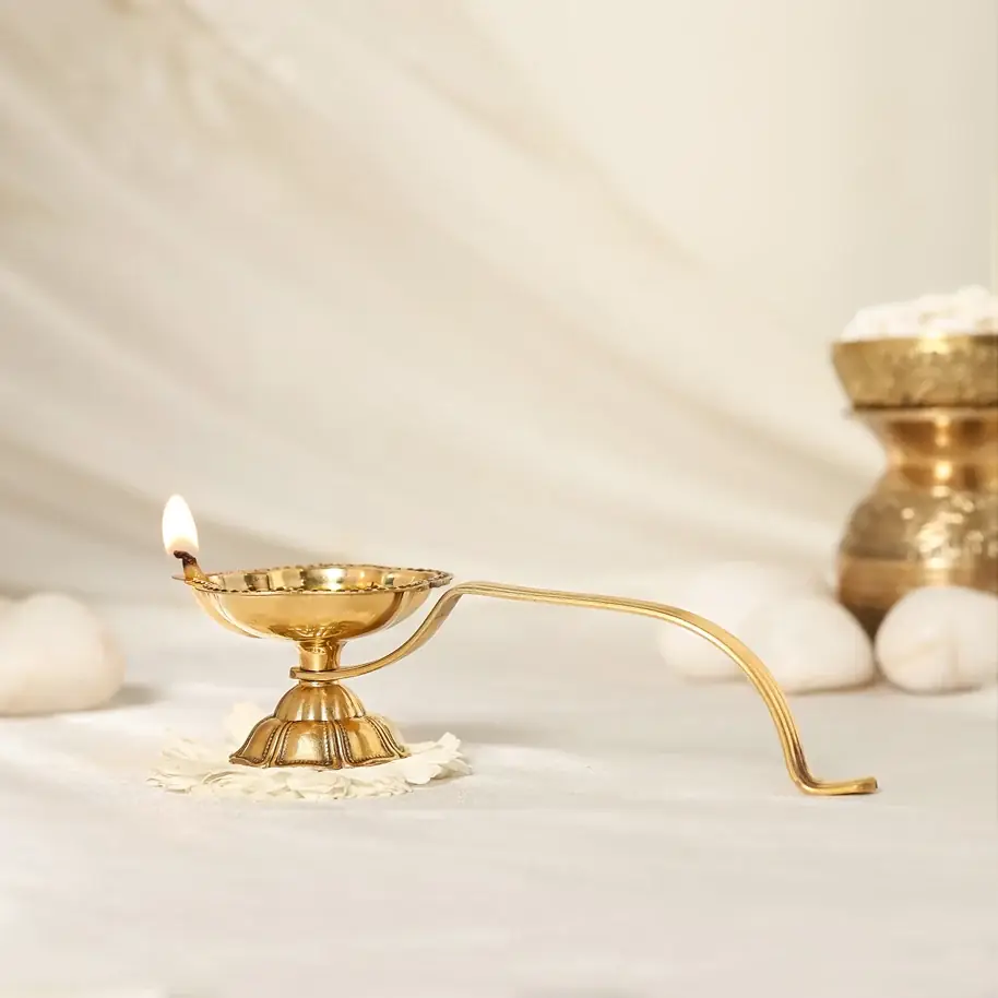 Brass aarti diya with its long handle, side view