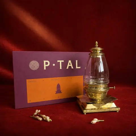 Brass akhand jyot diya lit on a dark green surface with marigolds
