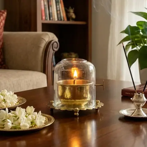 Brass diya under a glass dome on a table in a living room