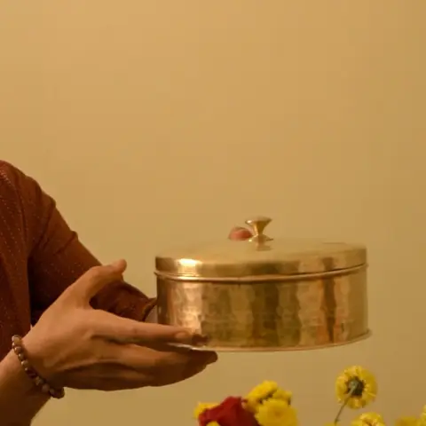 Box held in two hands in front of flowers