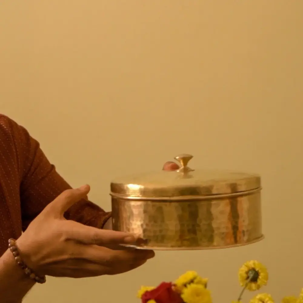 Box held in two hands in front of flowers