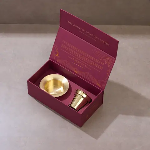 Open gift box with a brass tumbler and davara inside