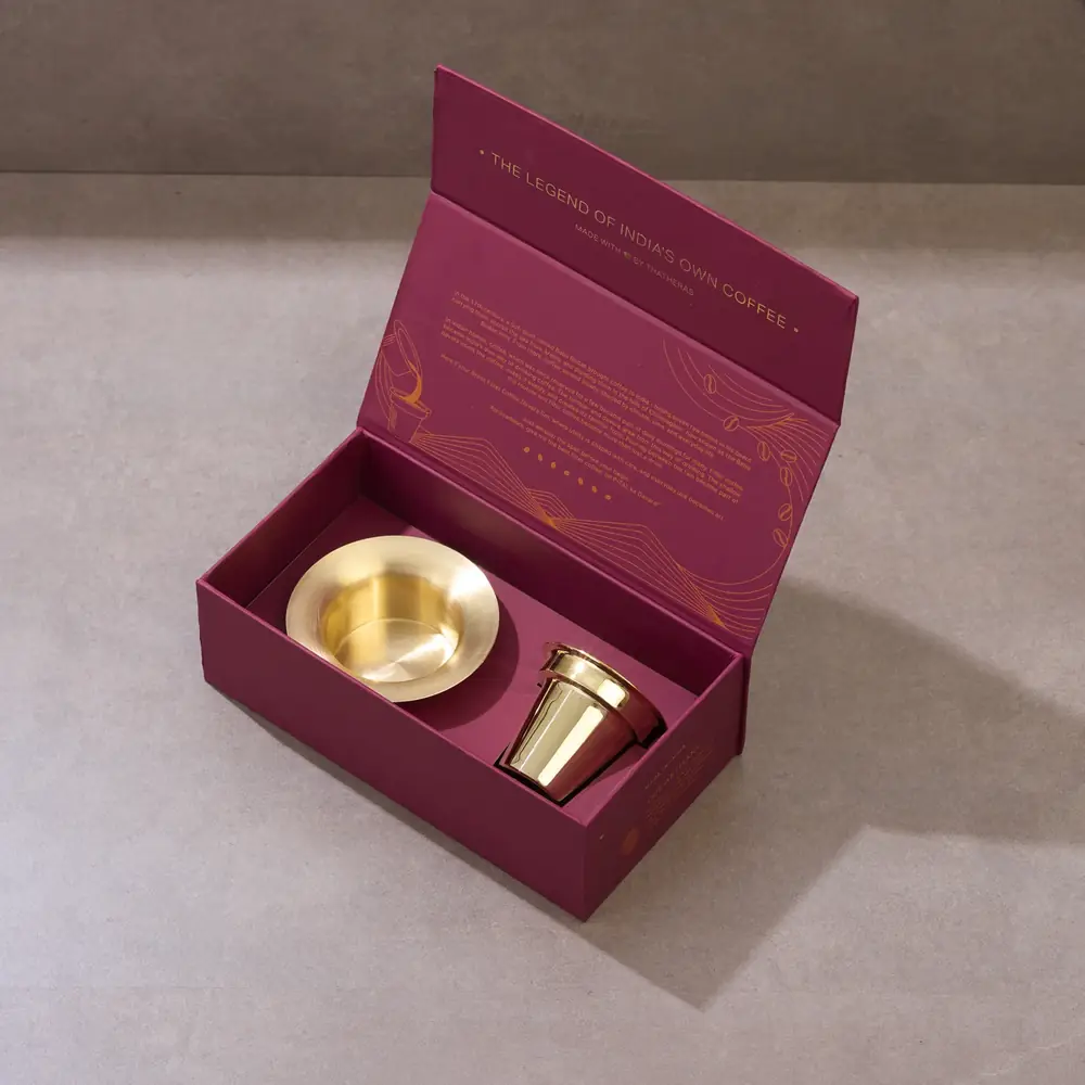 Open gift box with a brass tumbler and davara inside