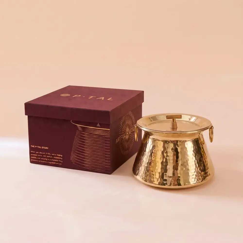 Brass degchi with its lid beside a dark gift box