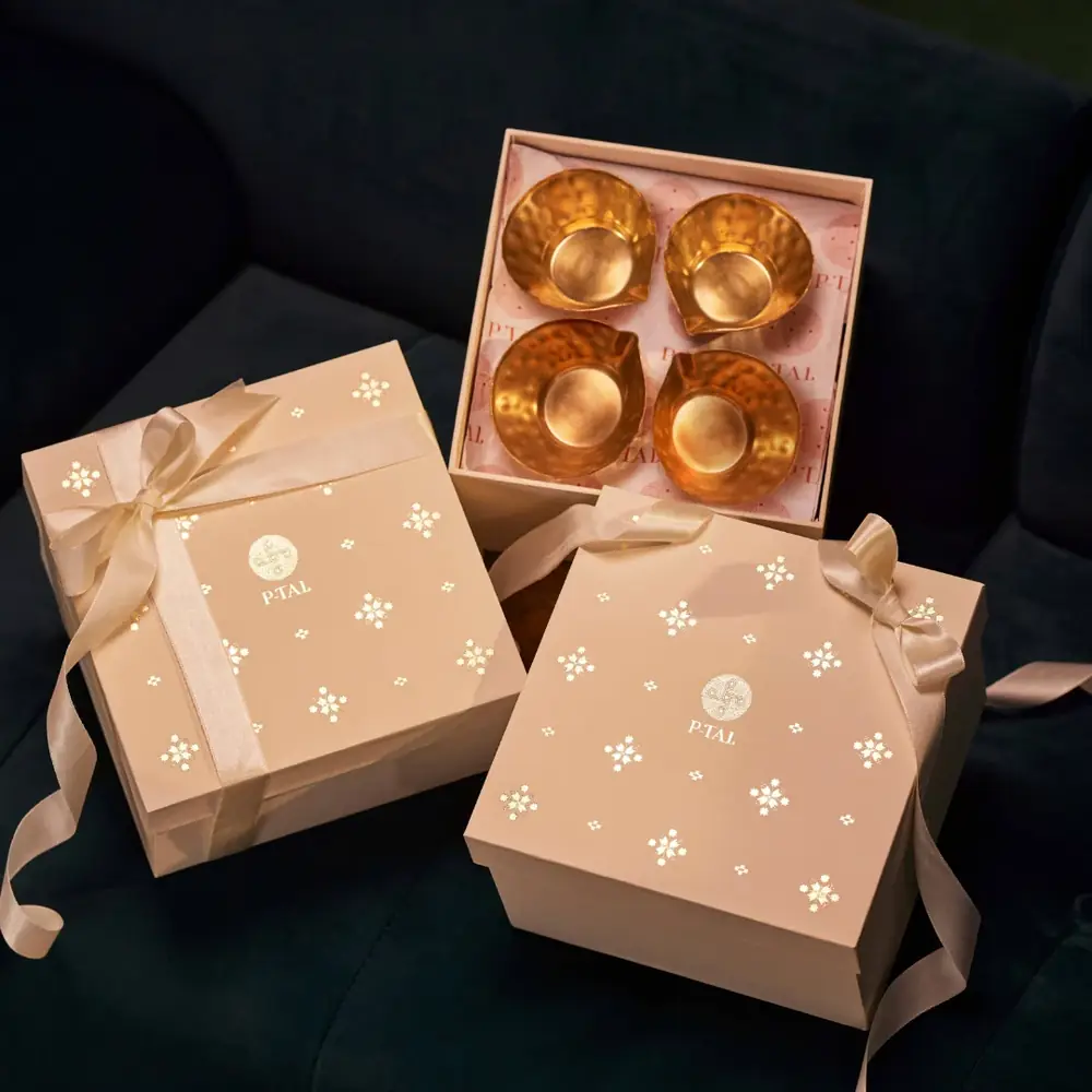 Open gift box with four brass diyas inside