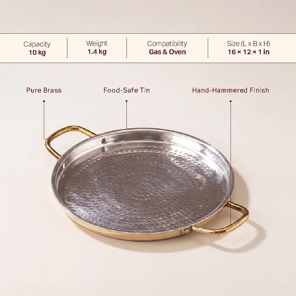 Hammered brass dosa tawa with two handles on a plain ground, with a strip of details above