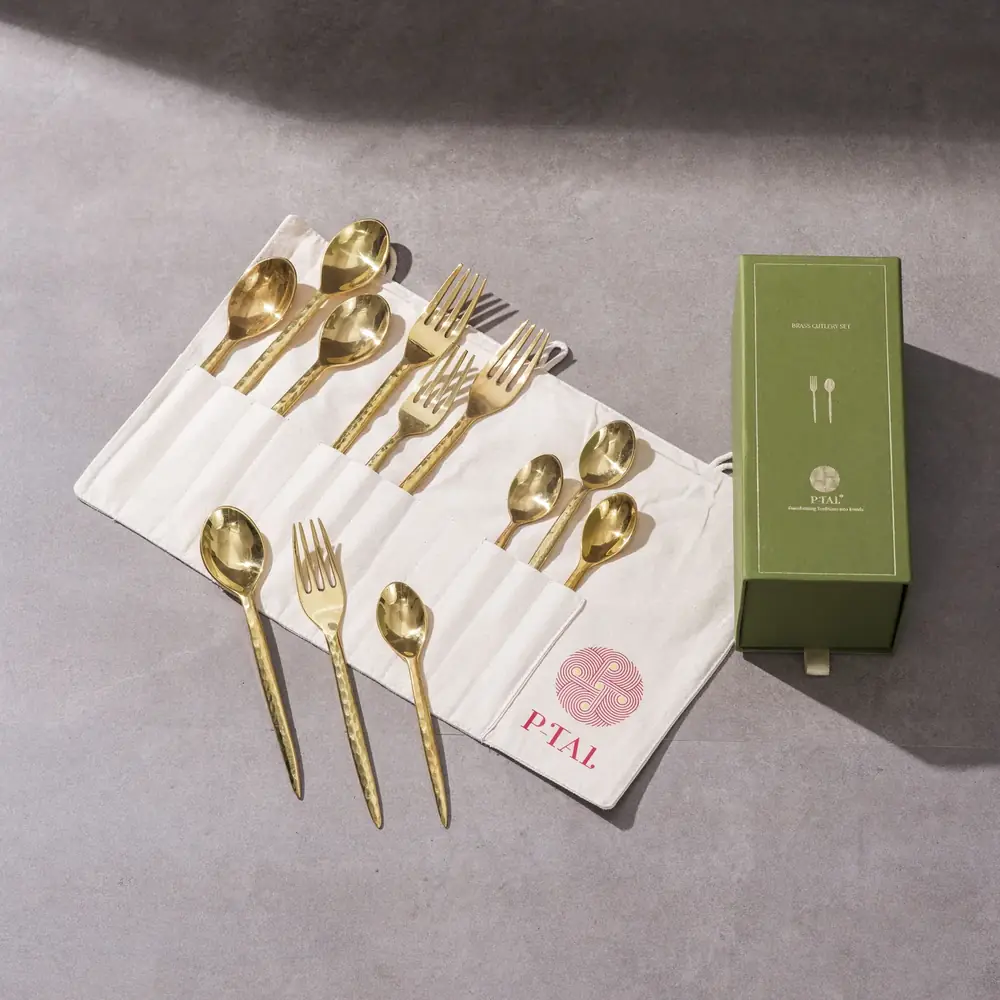 Brass cutlery laid on a cloth next to a green box