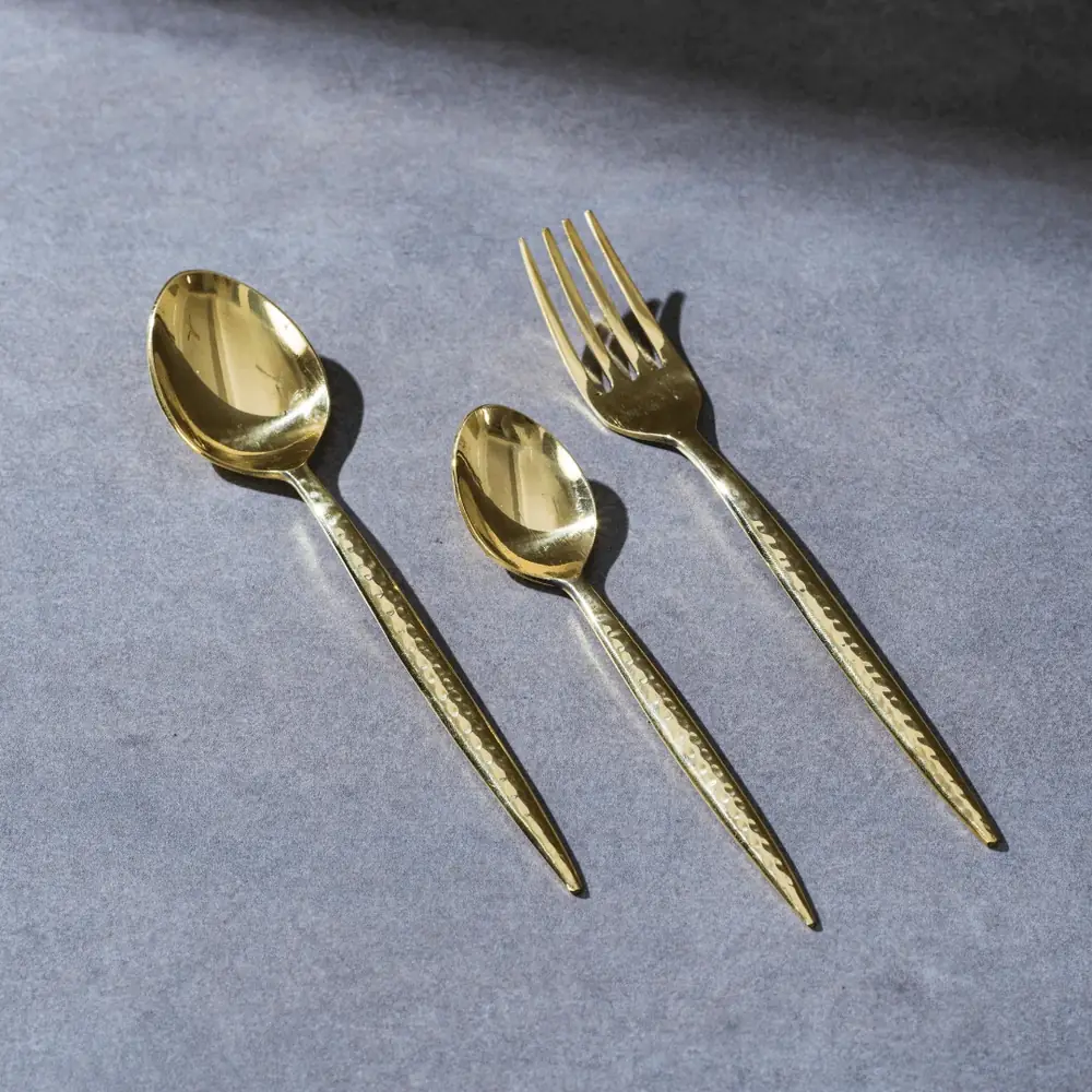 Brass spoon, fork and dessert spoon on a blue grey ground