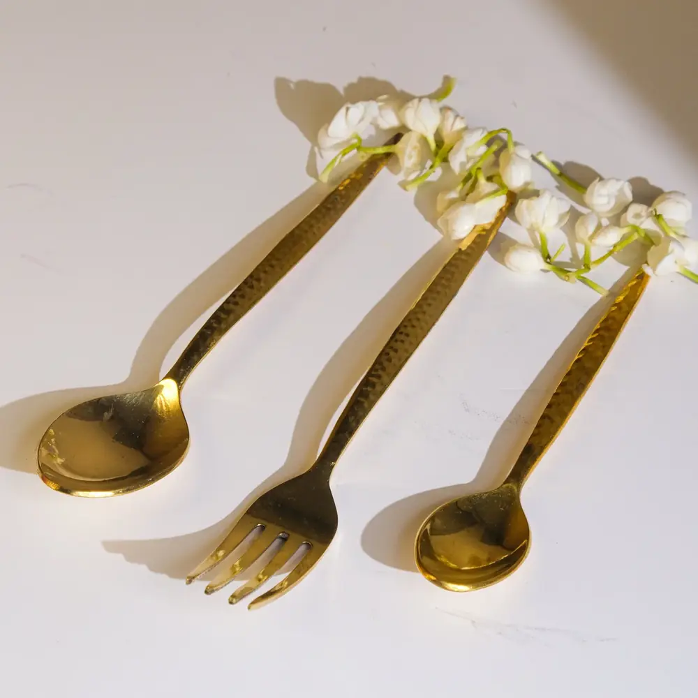 A brass spoon and fork with white flowers