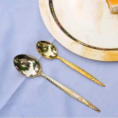 A hammered brass spoon on a blue cloth