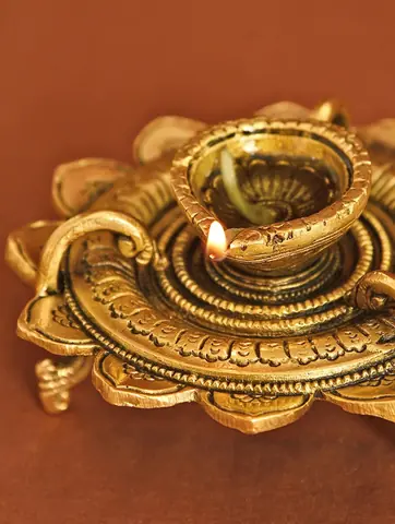 Lit diya with a wick in the bowl