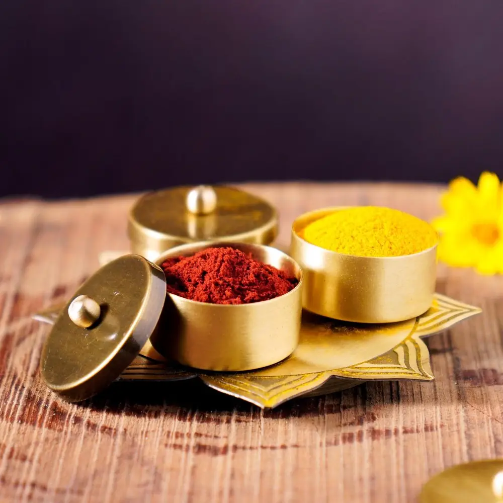 Brass lidded containers of kumkum and turmeric on a small tray