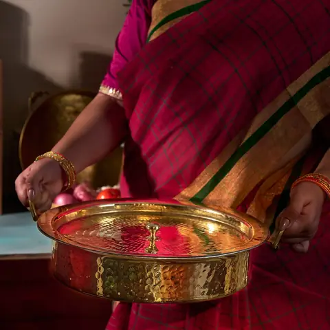 Woman in a sari holding the brass lagaan