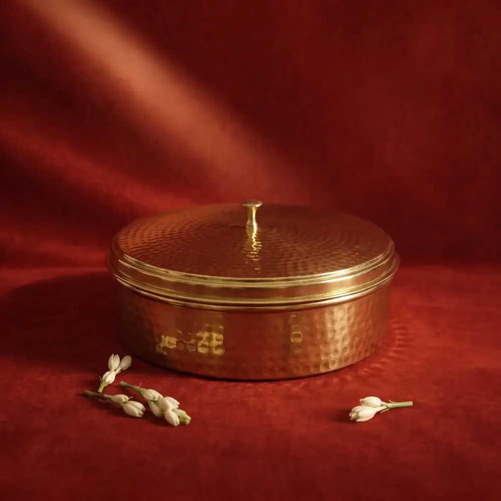 Closed hammered brass spice box on a red cloth