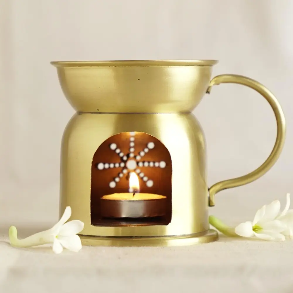 Brass oil burner with a handle and a lit lamp in the opening