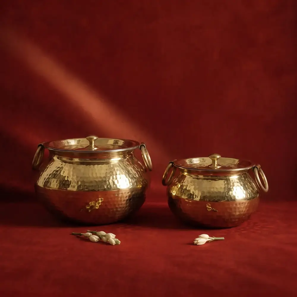 Two brass patilis on a dark red ground