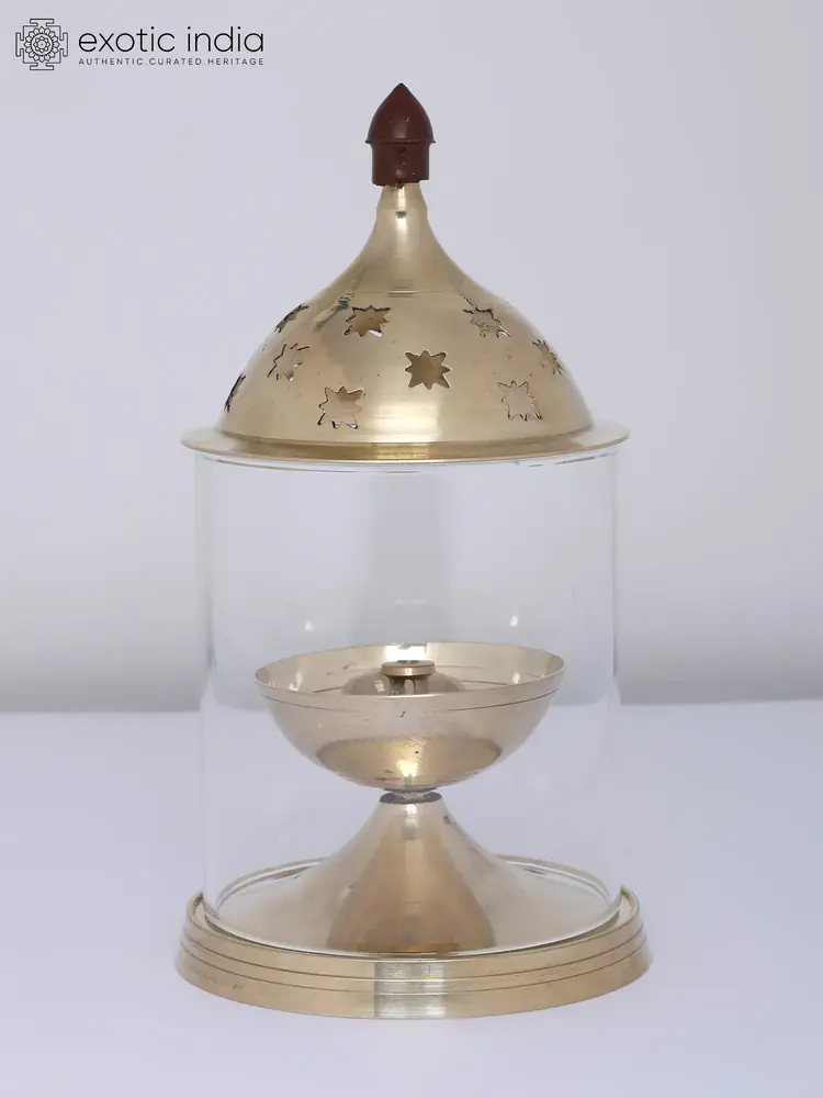 Brass lamp inside a glass cylinder with a pierced dome lid