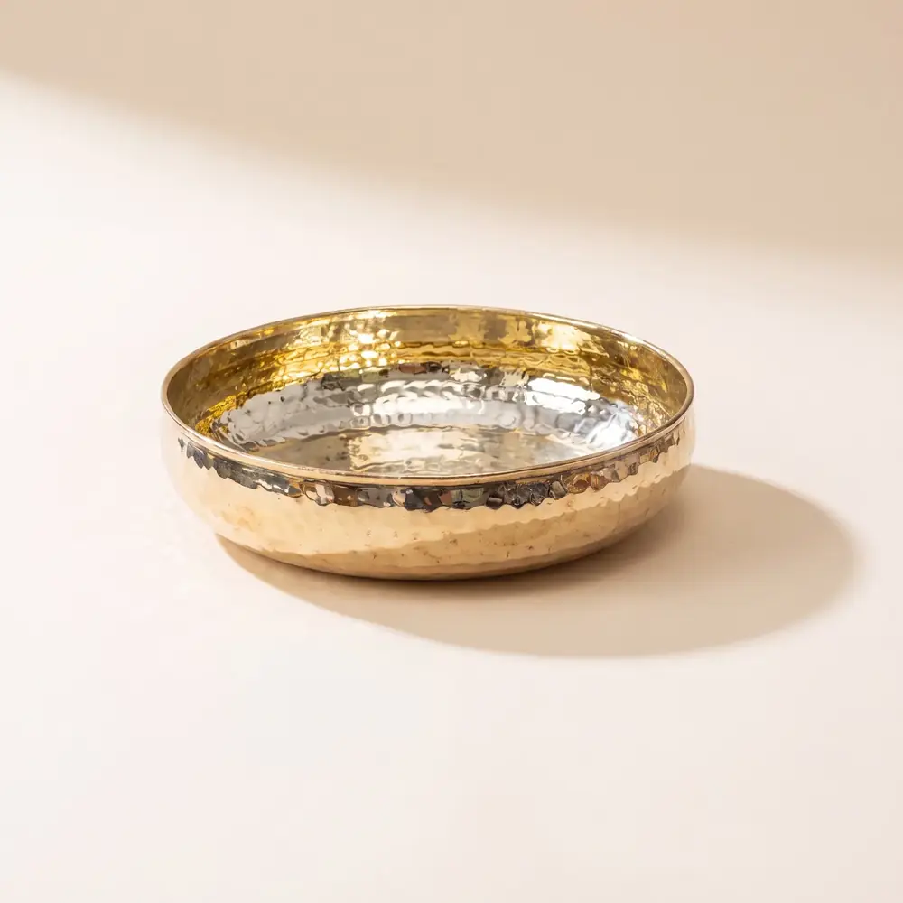 Brass urli bowl seen from the front on a plain ground