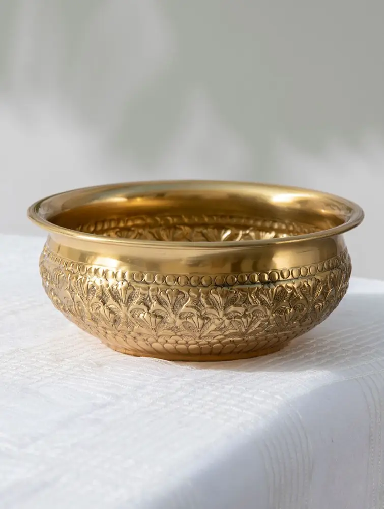 Brass urli on a white cloth, side view