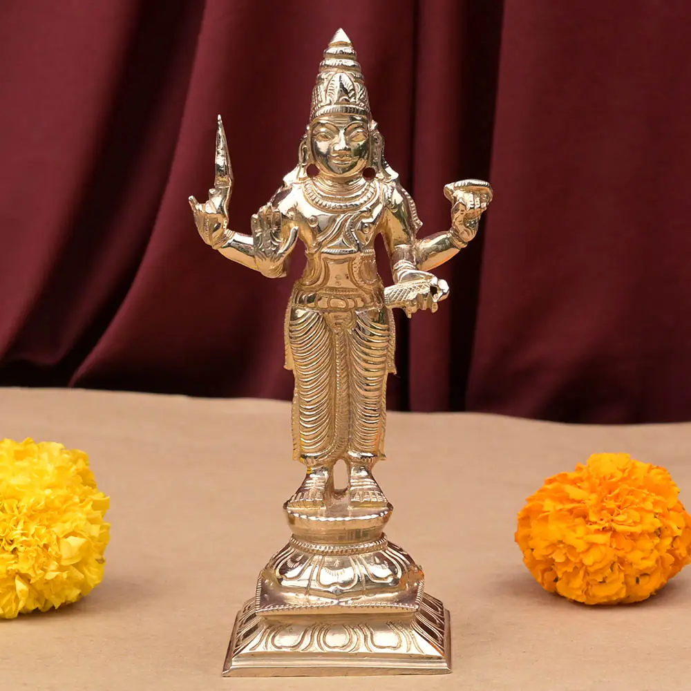 Budha bronze idol standing on its dais with marigolds