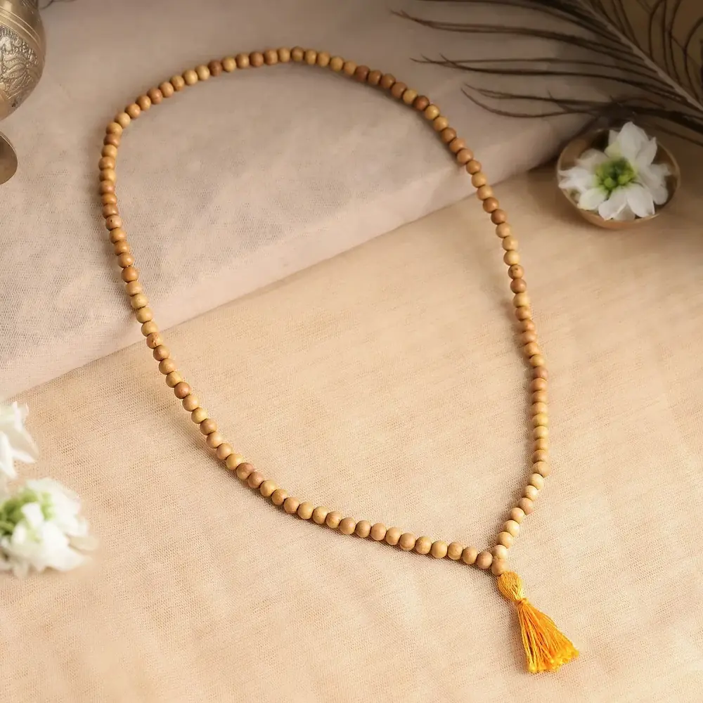 Sandalwood mala laid out with a yellow tassel on a cream cloth