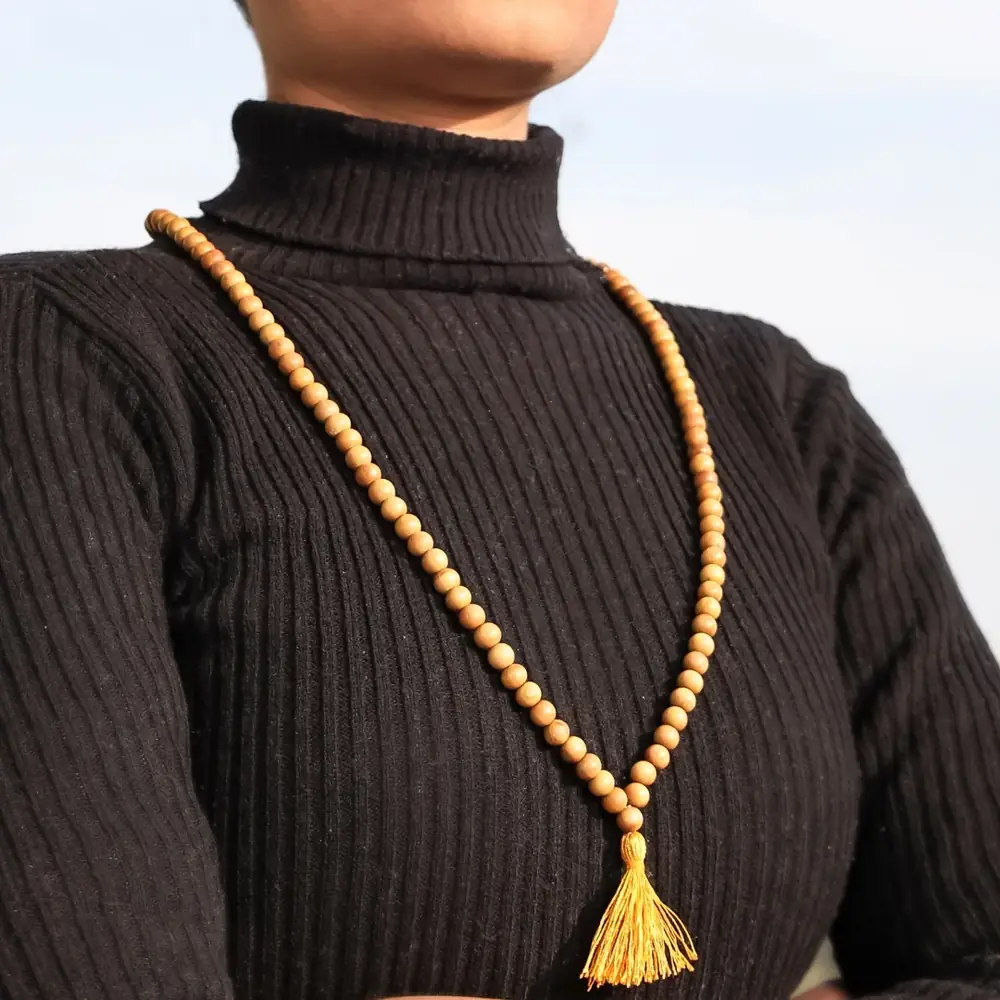 A person wearing the mala over a black polo neck