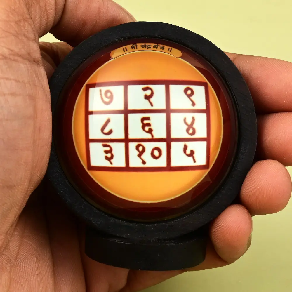 The framed yantra held in a hand for scale