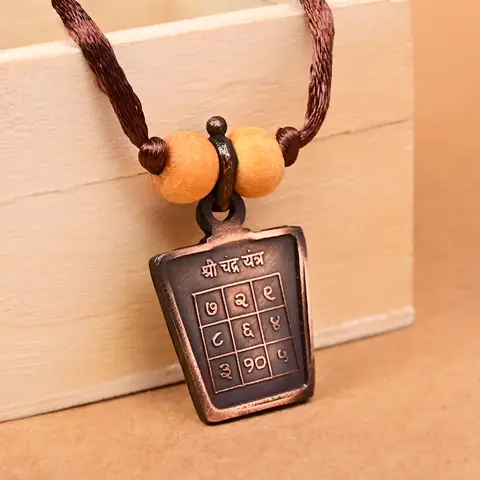 The yantra side on a brown cord with two beads