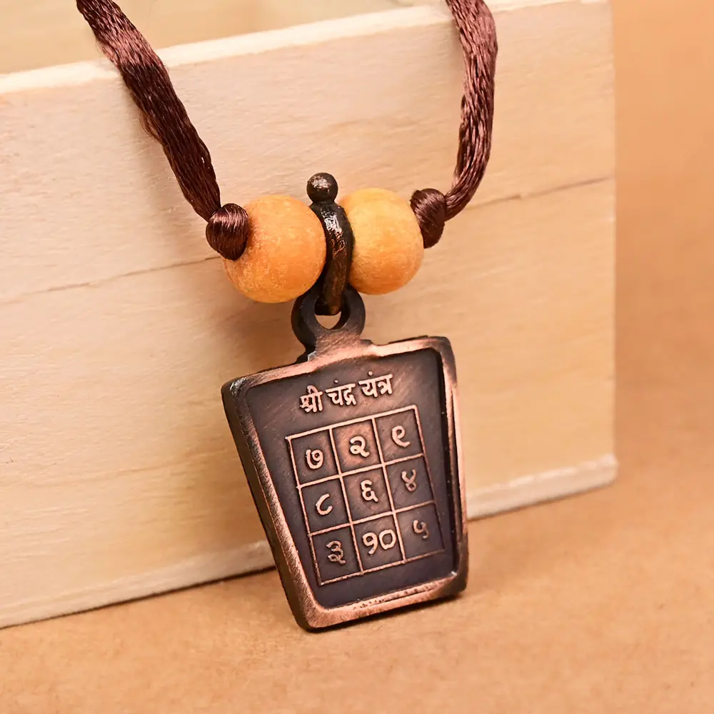 The yantra side on a brown cord with two beads