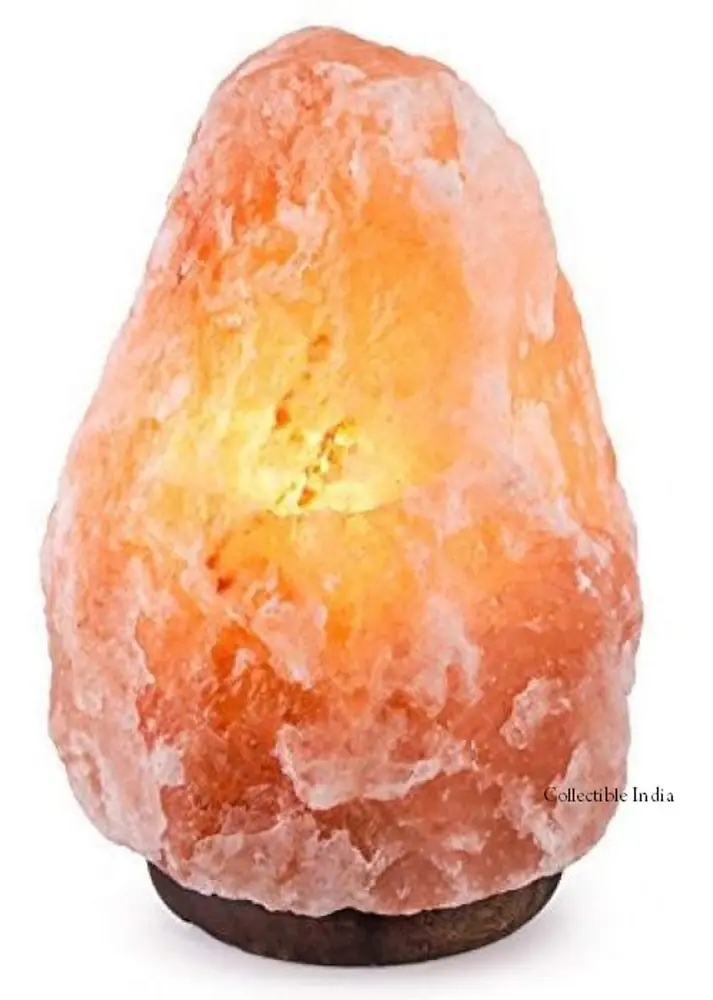 Lit pink and orange salt lamp on a wooden base with salt pieces beside it