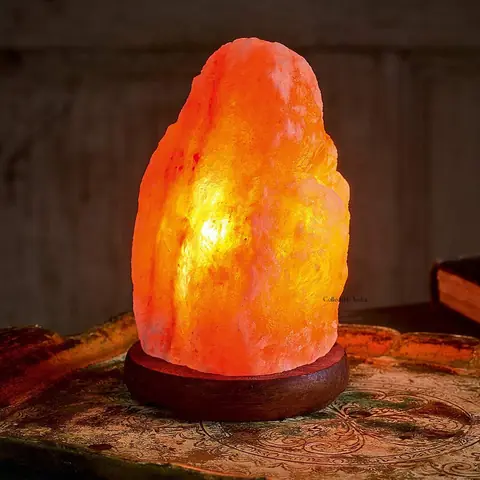 A lit salt lamp on a table with a small salt crystal