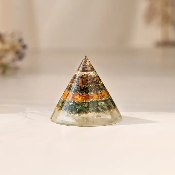 Cone shaped pyramid with orange and green stones on a white ground