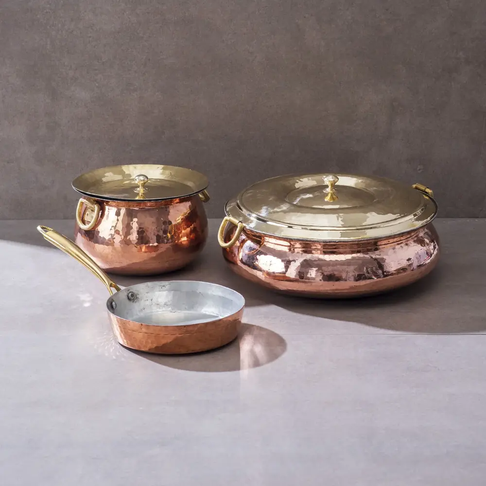 The three copper cooking pieces together on a grey ground