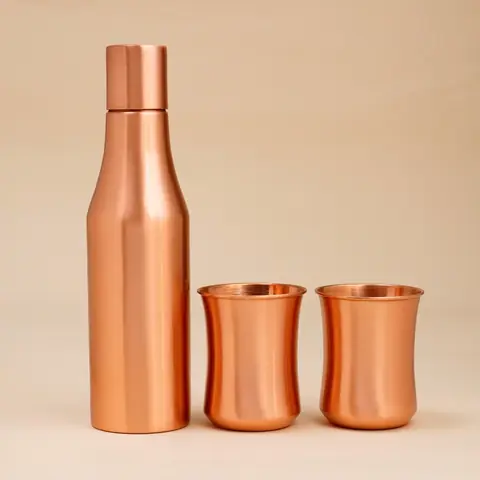 Copper bottle with two glasses on a plain ground